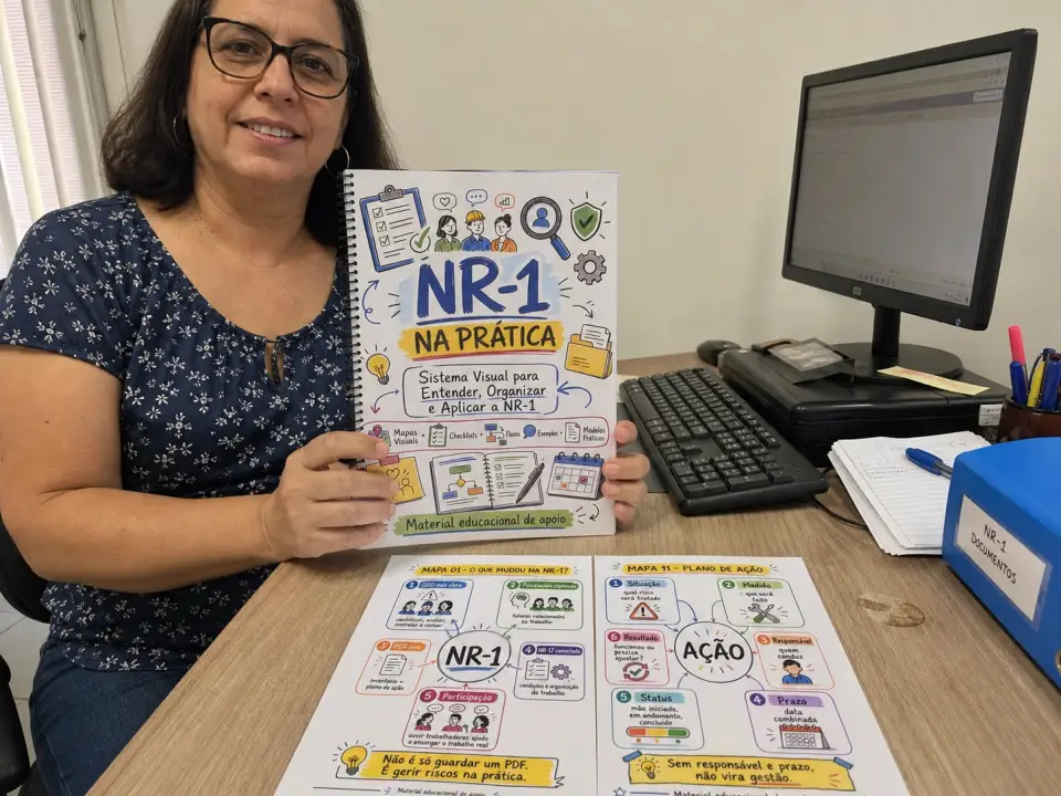 Profissional de RH em escritório simples segurando a apostila encadernada NR-1 na Prática com mapas reais na mesa